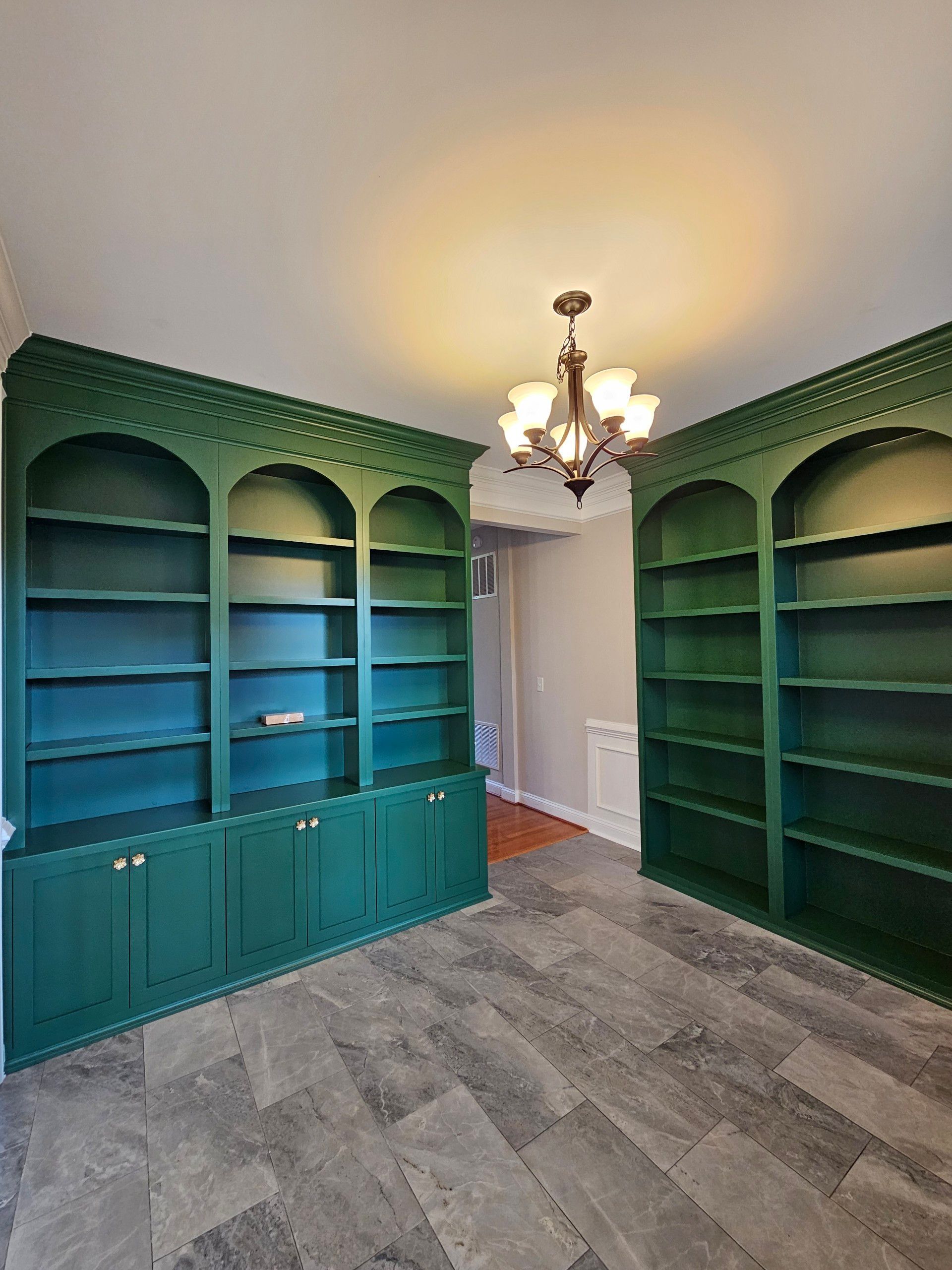 A room with green shelves and a chandelier hanging from the ceiling