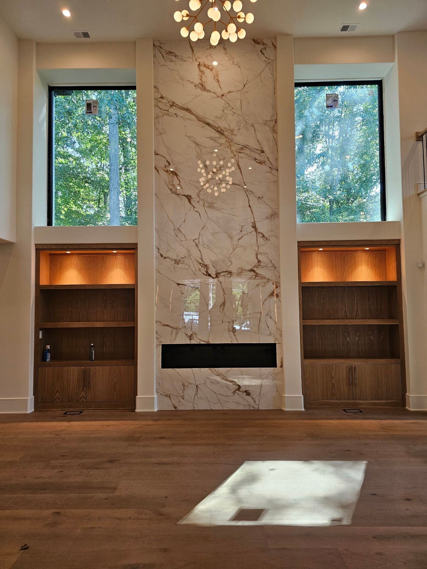 A living room with a marble fireplace and lots of windows