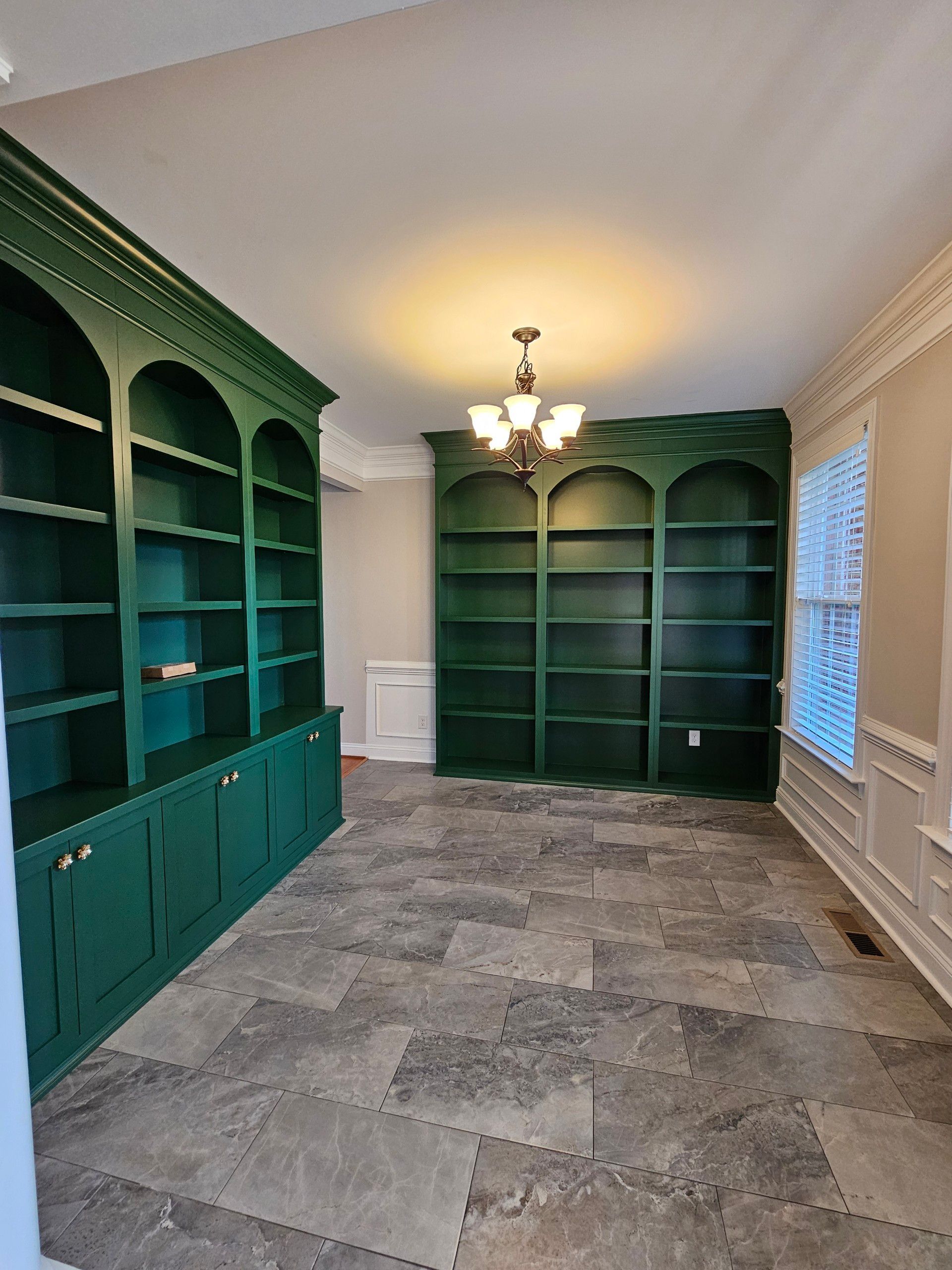 An empty room with green shelves and a chandelier