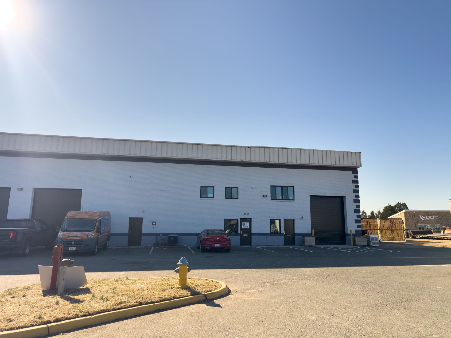 A white building with a red car parked in front of it