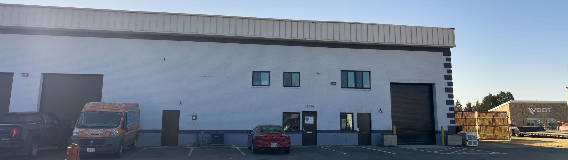 Three cars are parked in front of a large brick building.
