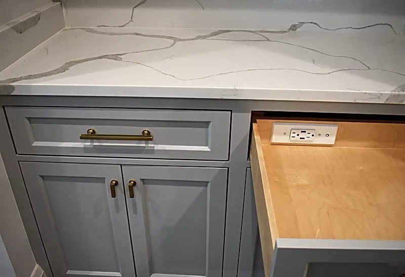A kitchen counter with a wooden drawer and a marble counter top.