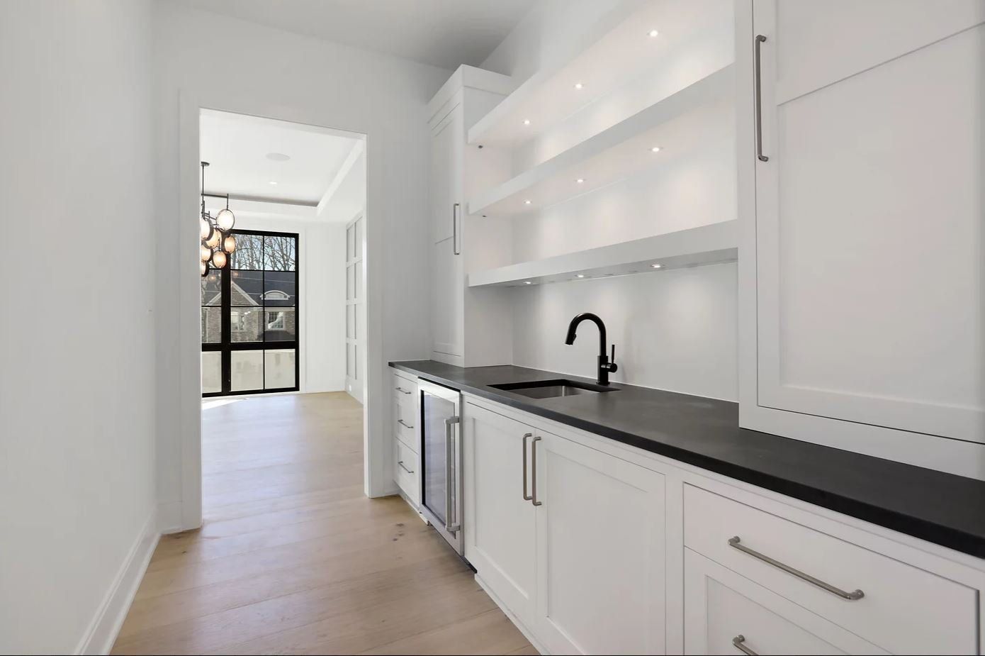 A kitchen with white cabinets and black counter tops
