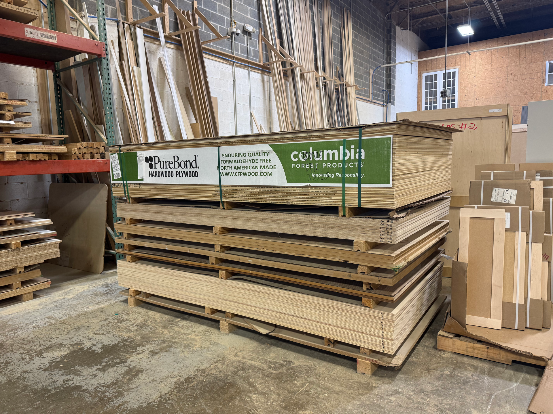 A pallet of Columbia brand wood boards stacked in a warehouse, near other stored lumber.