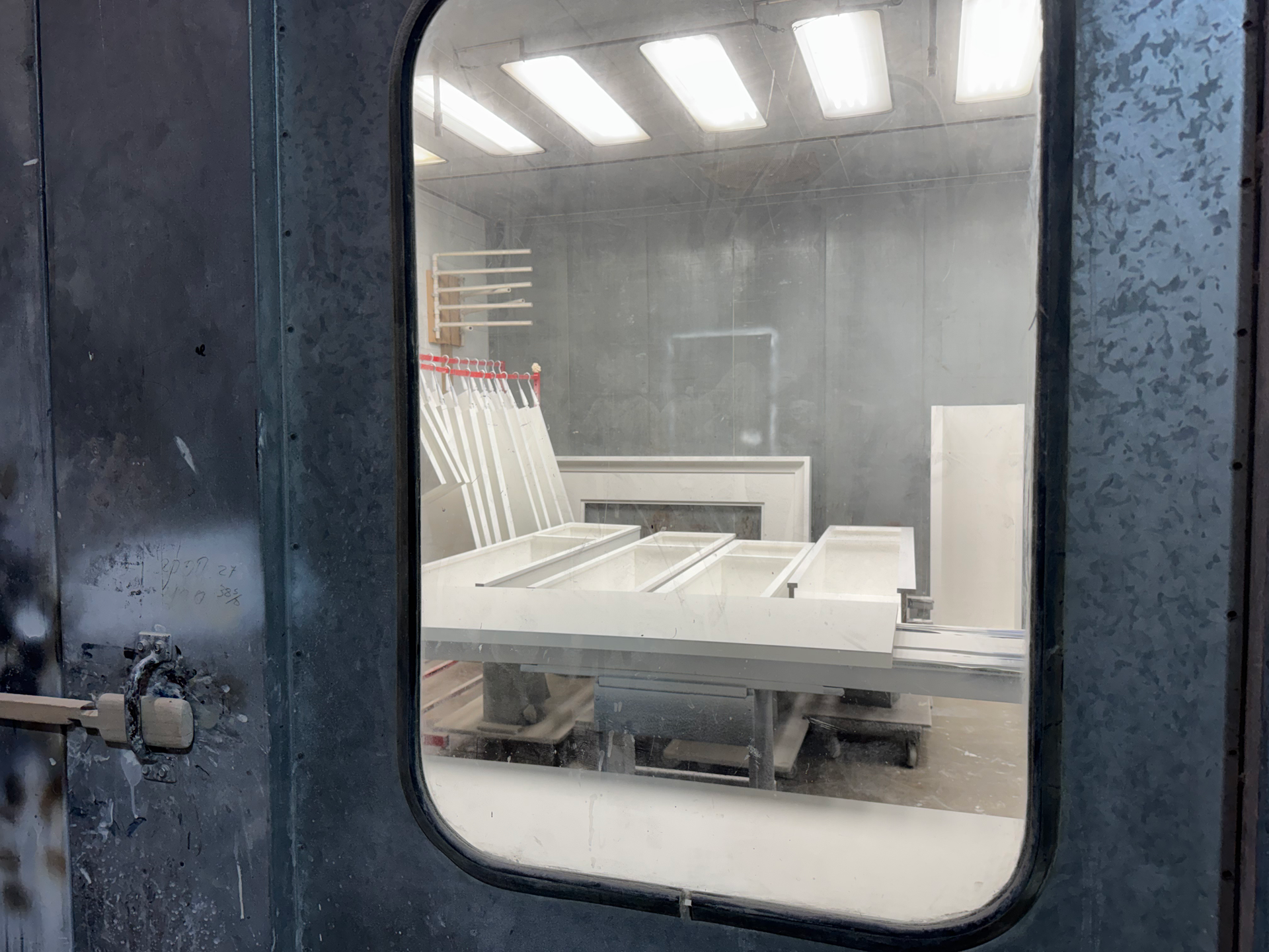 A spray paint booth filled with white cabinets. A worker is likely applying paint.
