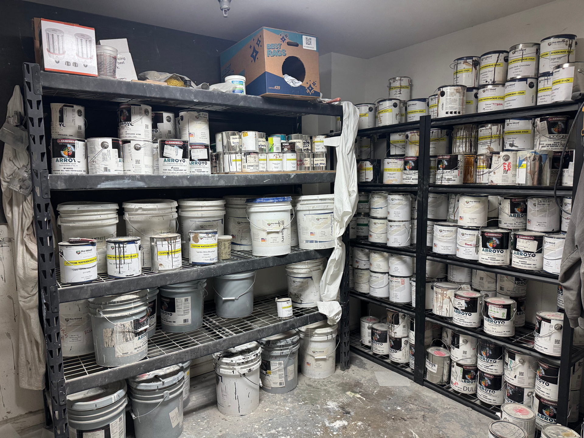 Shelves filled with paint cans in a messy storage area.