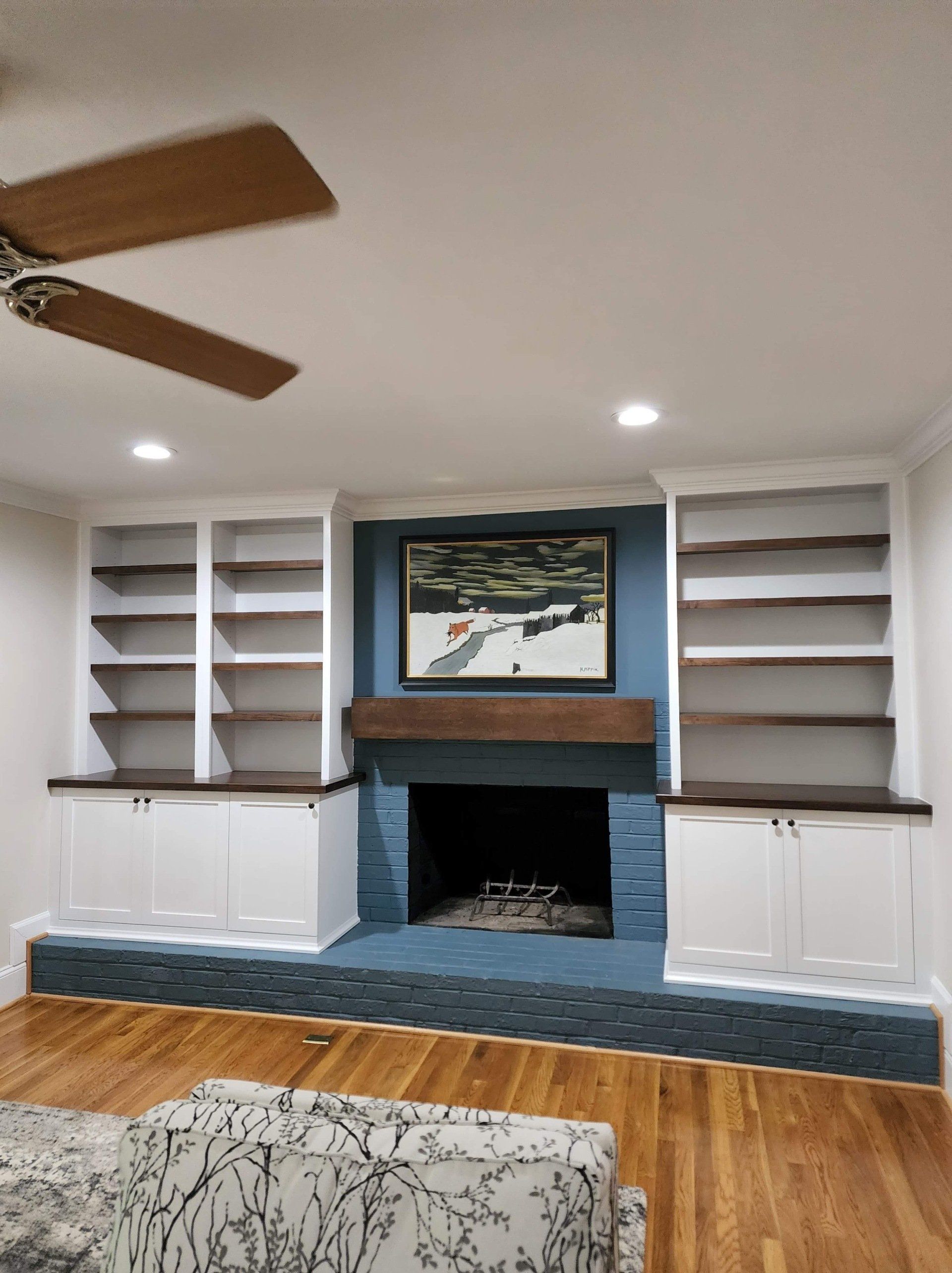 A living room with a fireplace and a ceiling fan