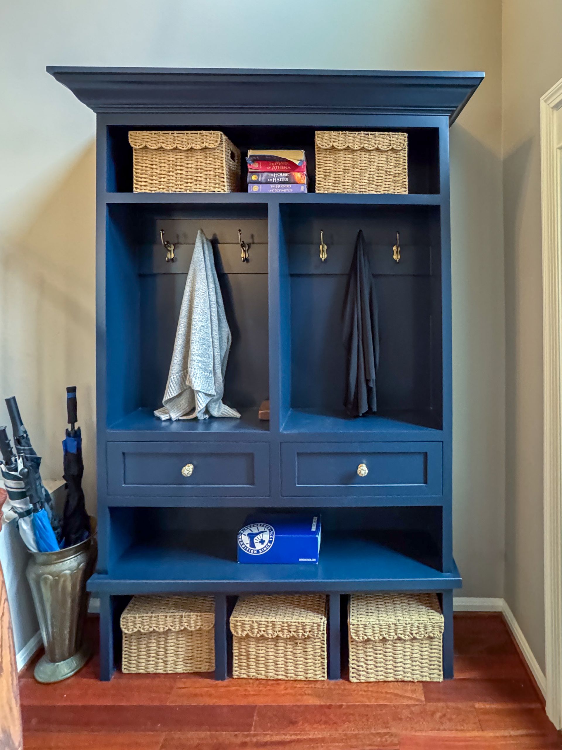 A blue cabinet with wicker baskets and hooks