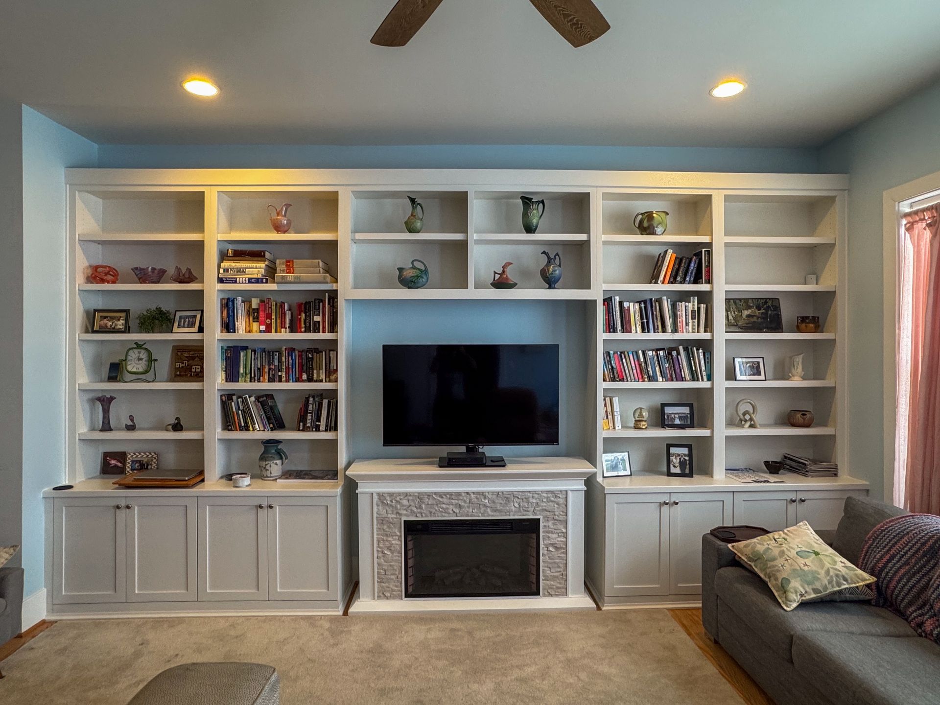 A living room with lots of shelves and a fireplace