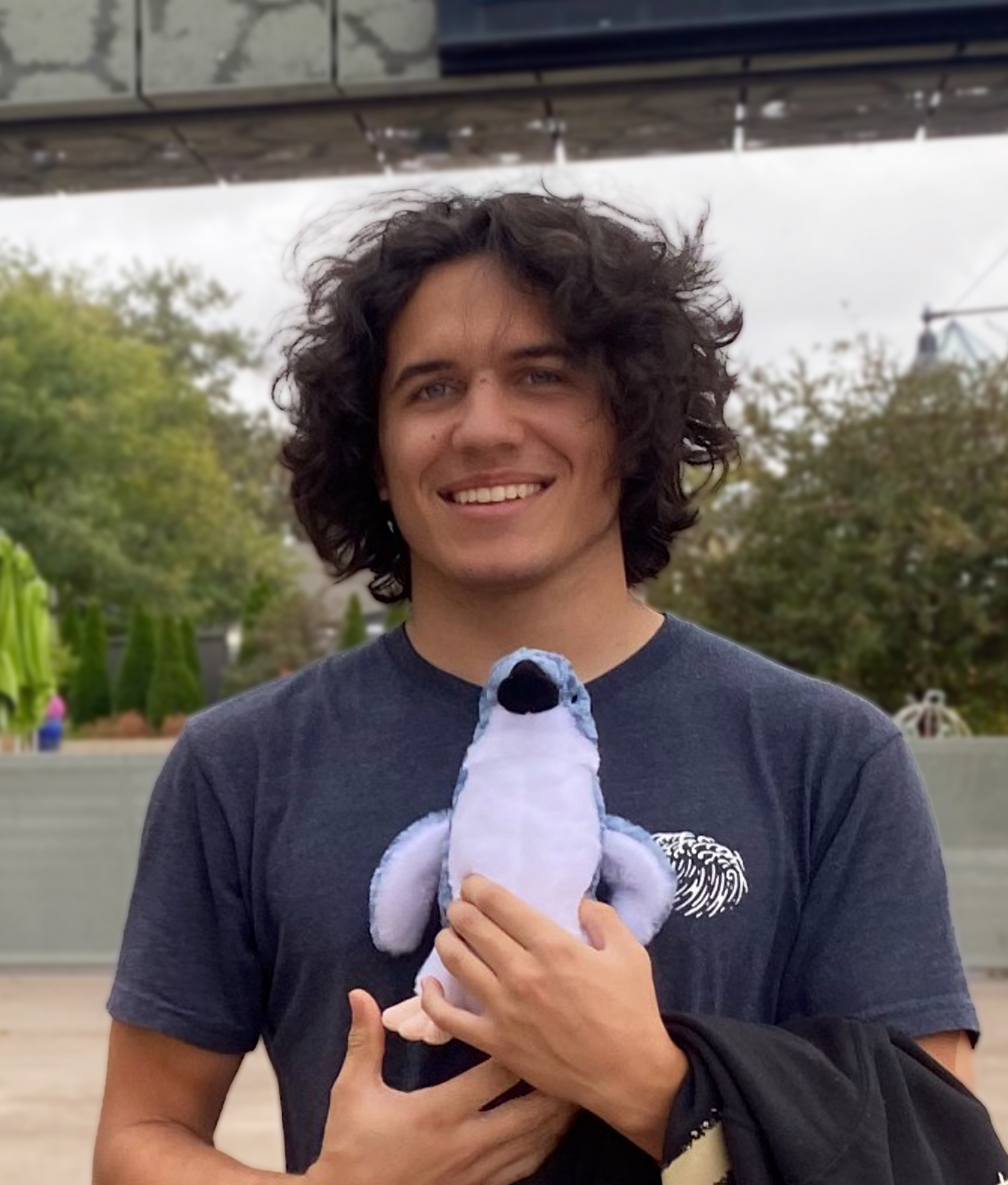 A man holding a stuffed animal in front of a sign that says welcome