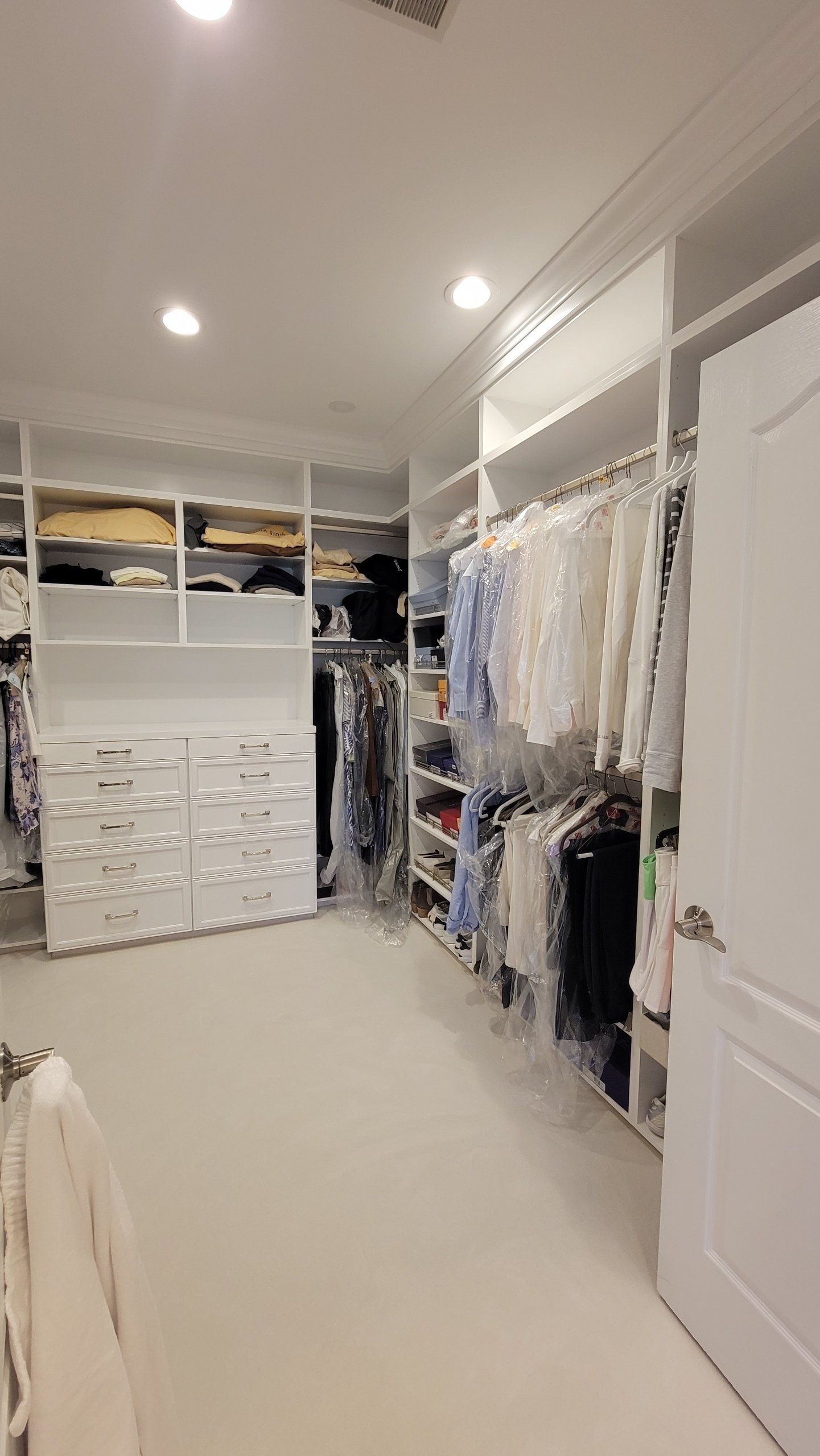 A walk in closet filled with lots of clothes and shoes.