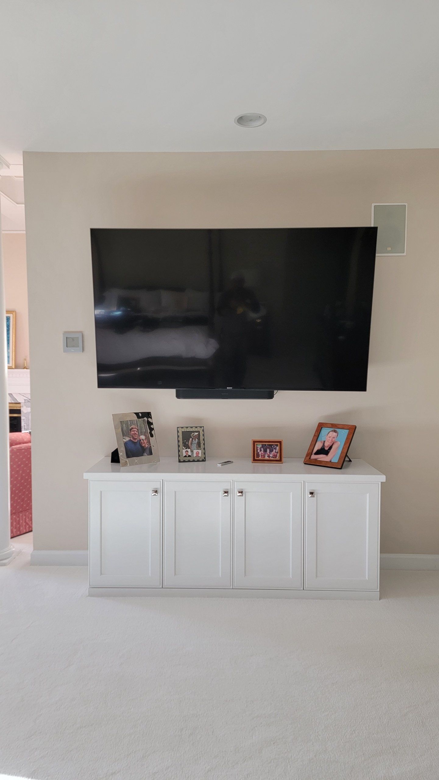 A large flat screen tv is mounted on the wall above a white cabinet
