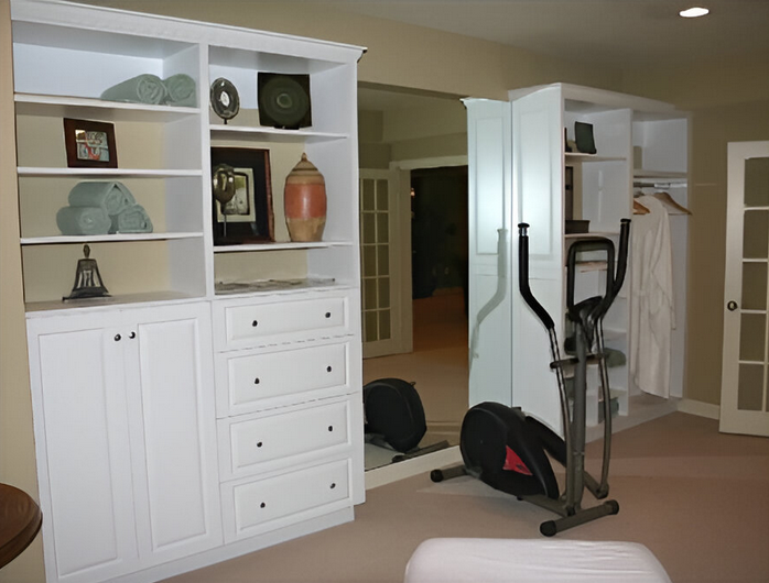 A room with white cabinets and a black elliptical