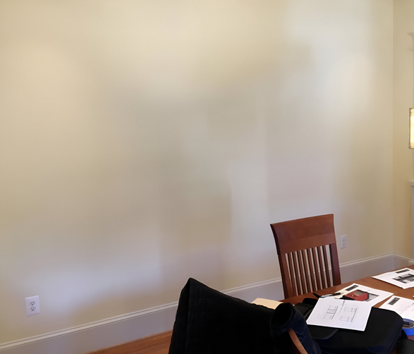 A dining room with a table and chairs and a white wall