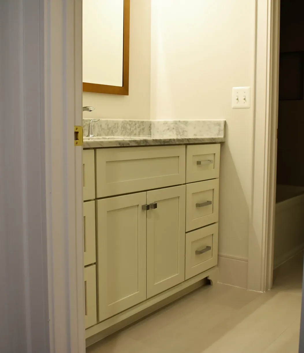 A bathroom with white cabinets and marble counter tops