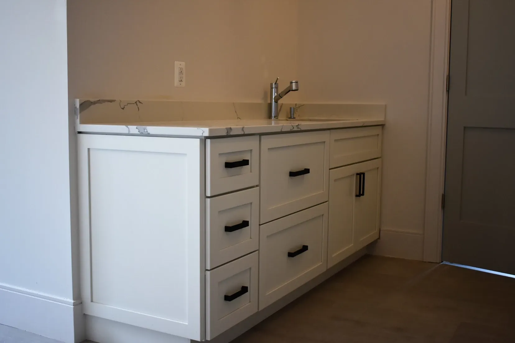 A kitchen with white cabinets and black handles