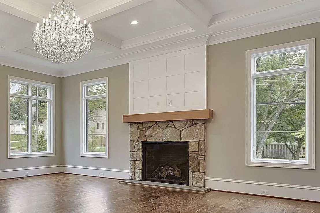 An empty living room with a fireplace and a chandelier.