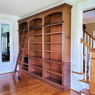 A large wooden bookshelf with a ladder attached to it.