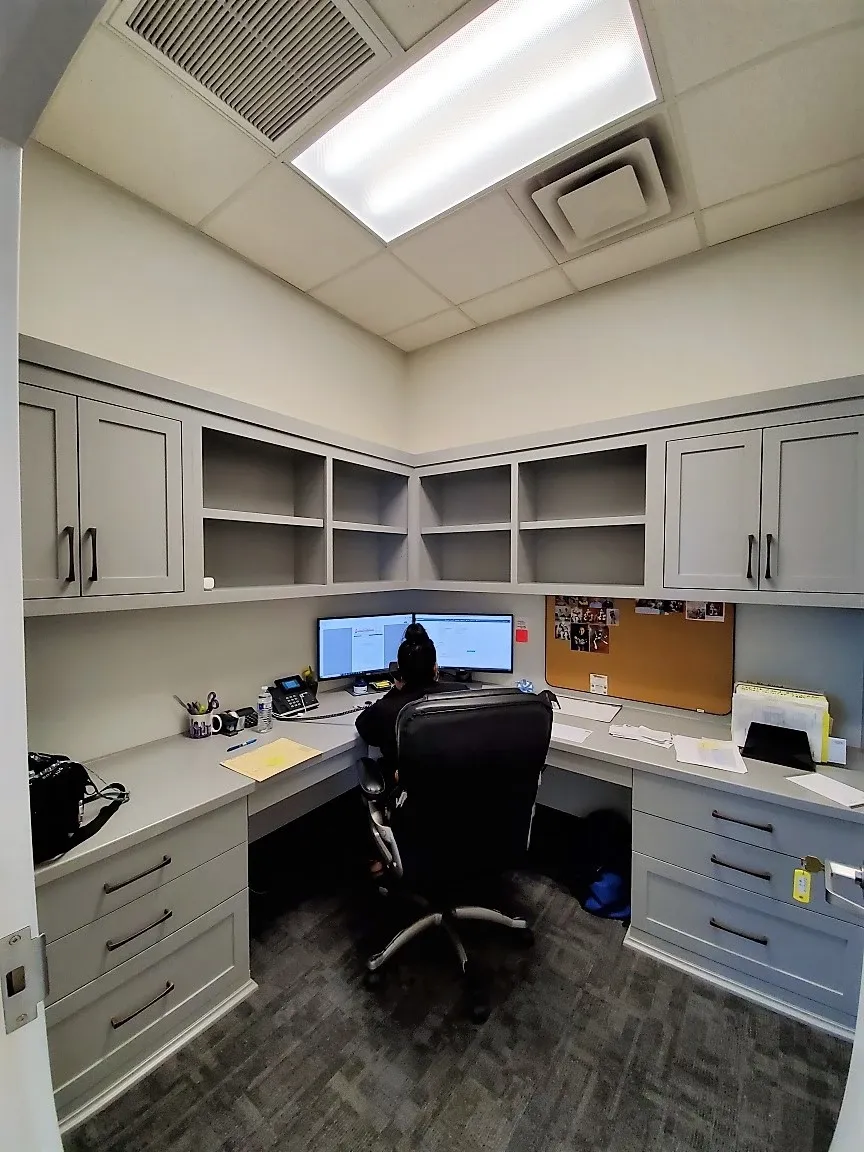 A man sits at a desk in a small office