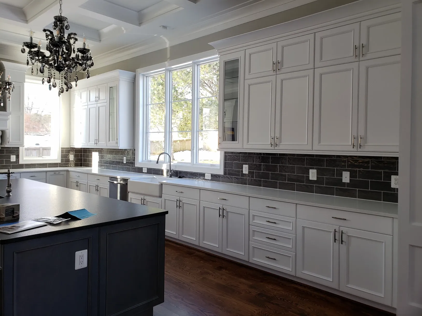 A kitchen with white cabinets and a black island