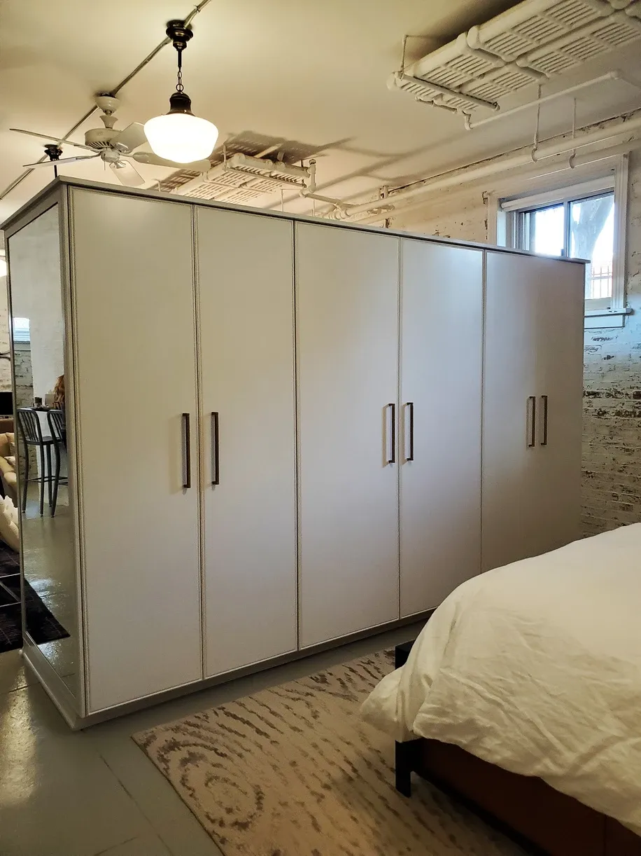 A bedroom with white cabinets and a bed