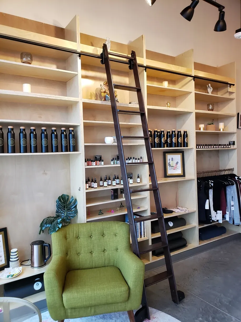 A green chair sits in front of a ladder in a store