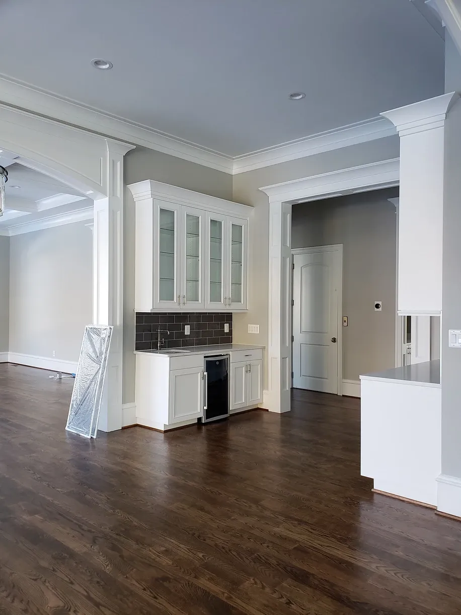 A kitchen with white cabinets and hardwood floors