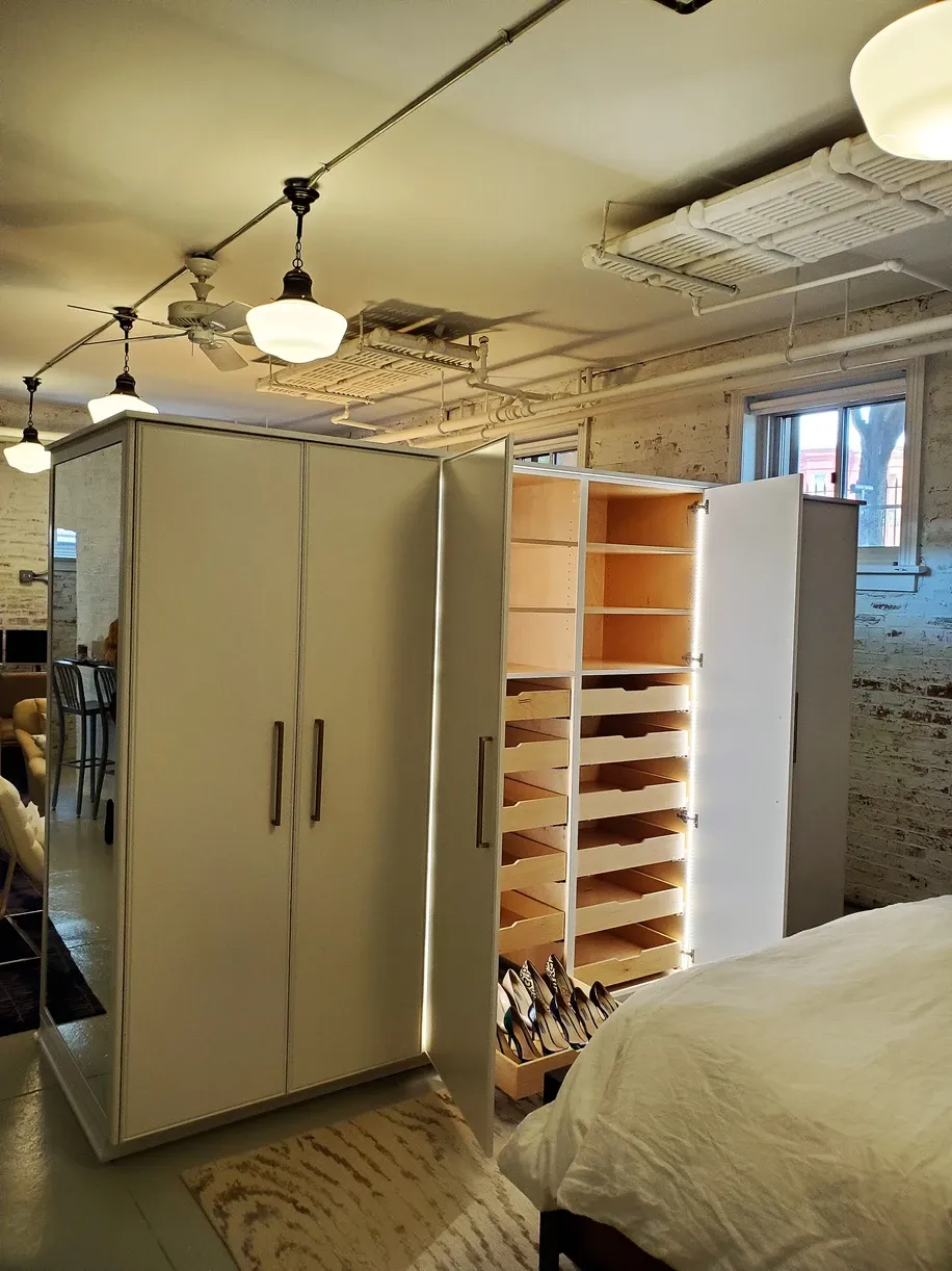 A bedroom with a bed and a closet behind it