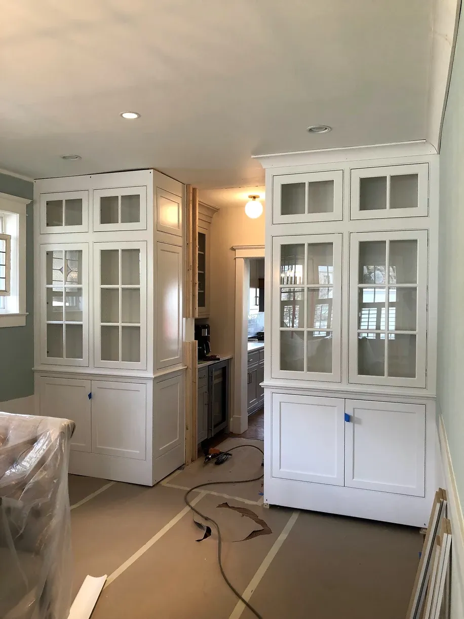 A room with a lot of white cabinets and glass doors