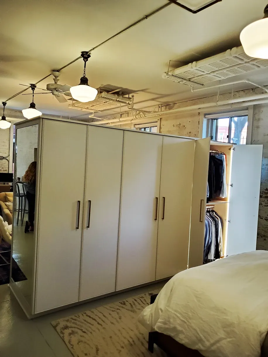 A bedroom with white cabinets and a bed