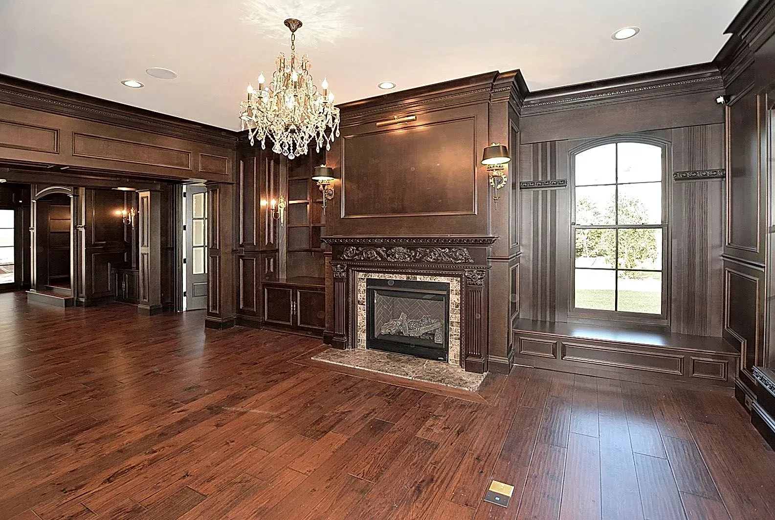 An empty room with a fireplace and a chandelier