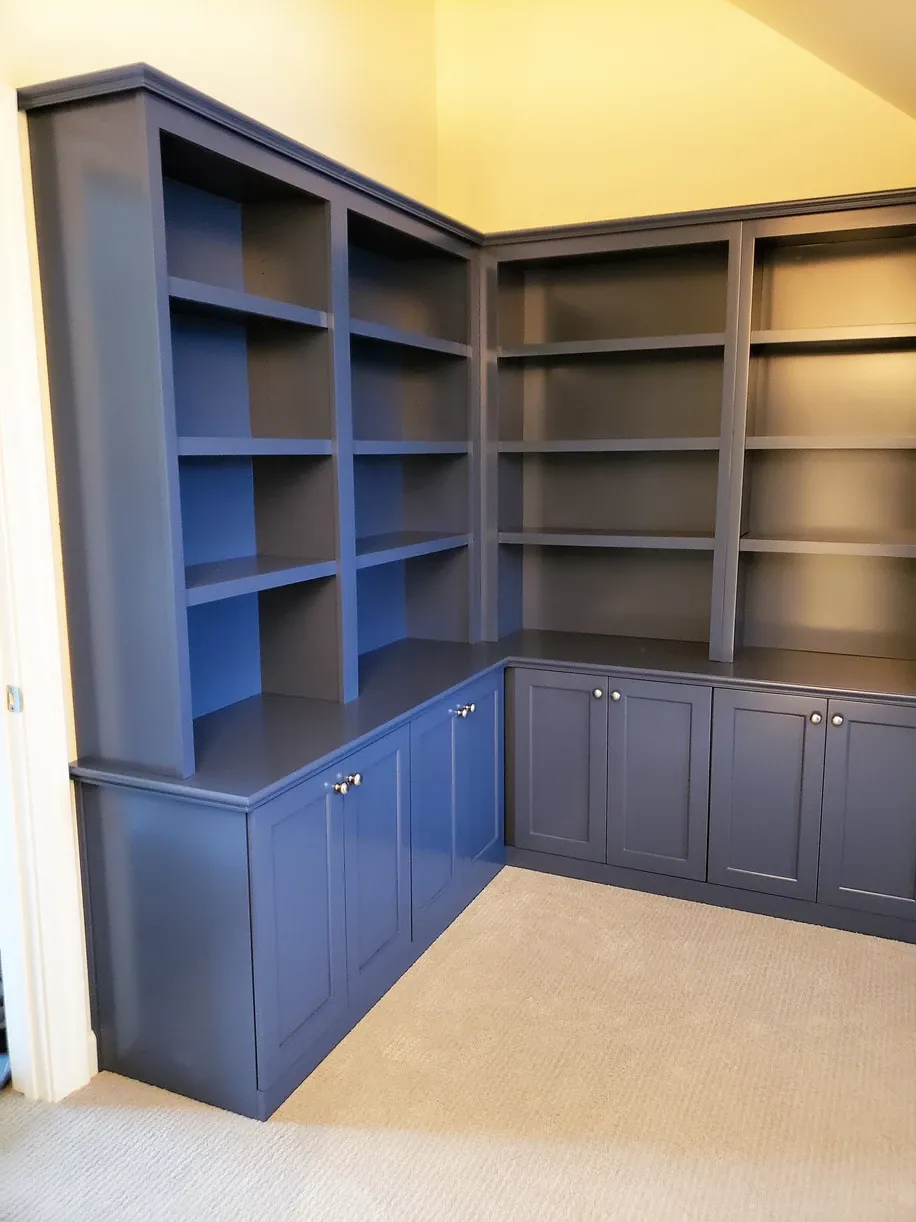 A corner of a room with blue cabinets and shelves