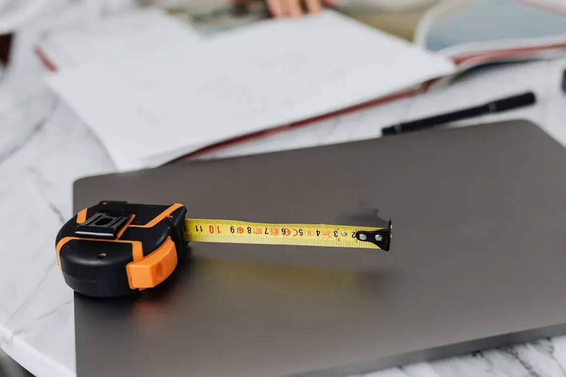 A tape measure is laying on top of a laptop