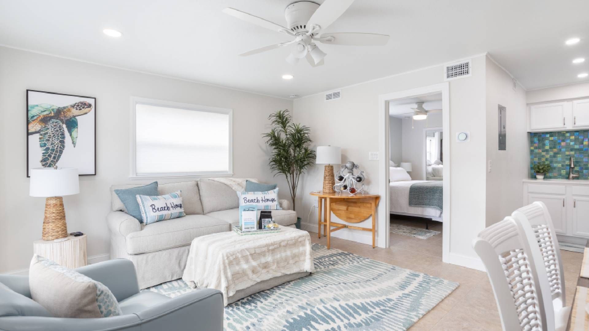 Bright white beach condo living room with wood and wicker furniture near Sarasota, FL