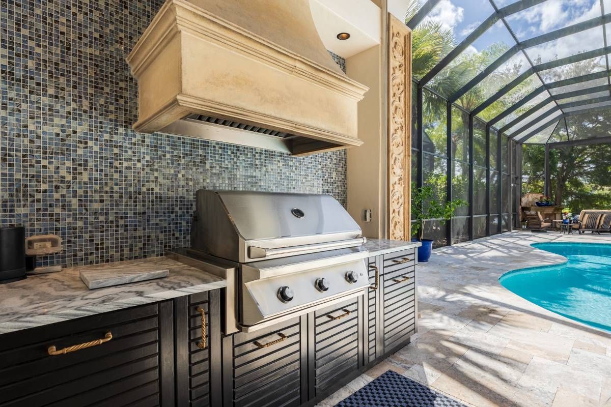 A luxury lanai design featuring an outdoor grill, fume hood, countertop, cabinets, and swimming pool at Divine Interiors Group near Lakewood Ranch, Florida (FL)