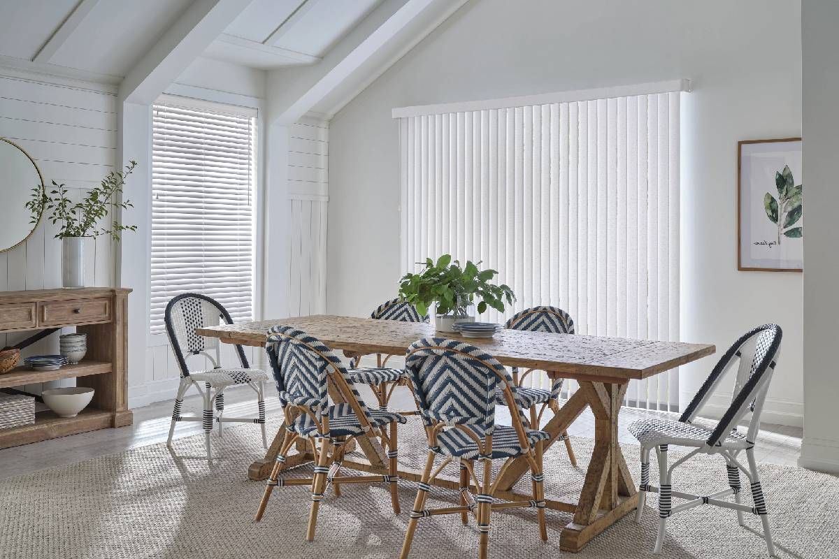 Modern kitchen with a wooden table and sliding glass door covered with Hunter Douglas Vertical Solutions® Vertical Blinds at Divine Interiors Group near Lakewood Ranch, FL