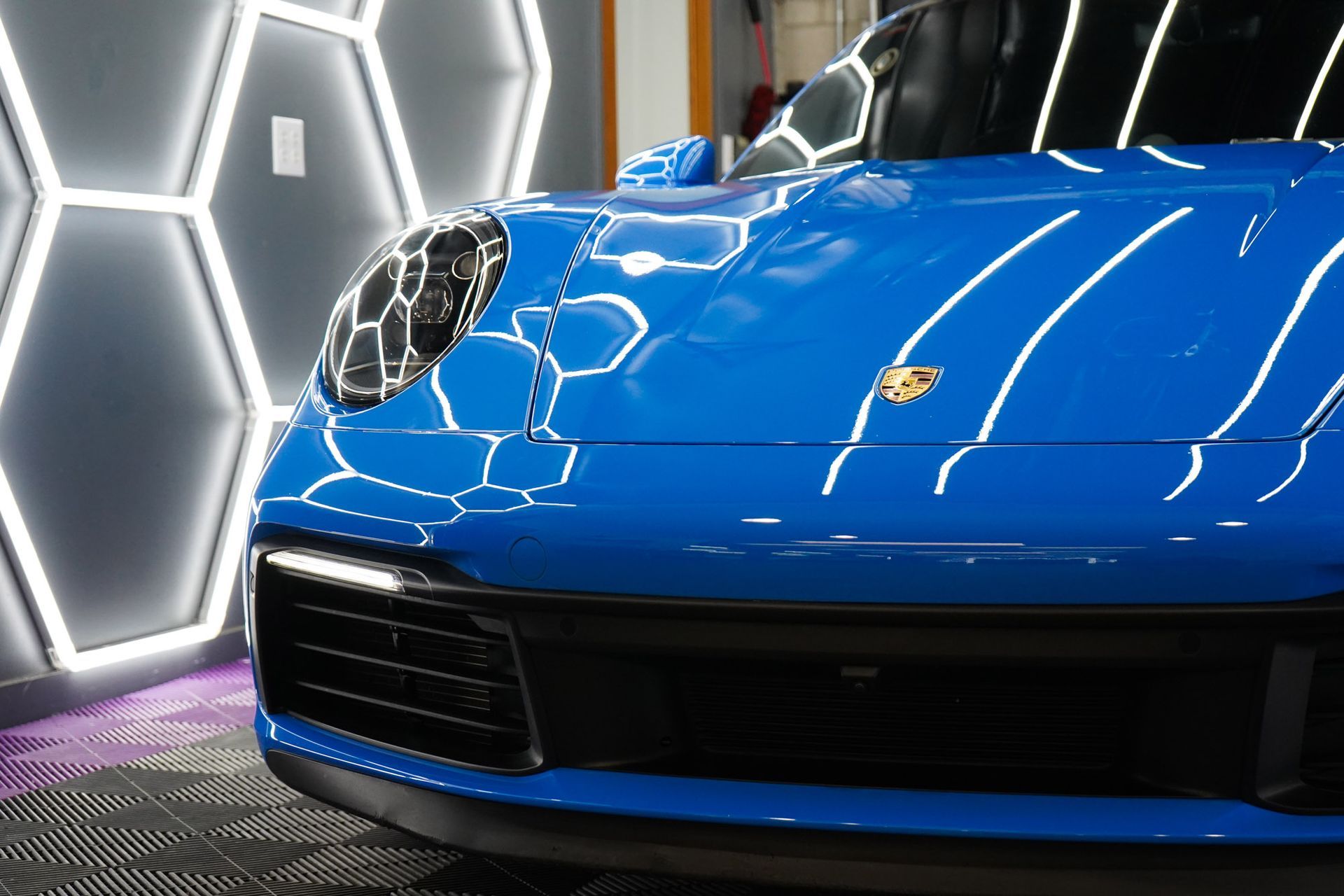 A blue porsche 911 is parked in a garage.