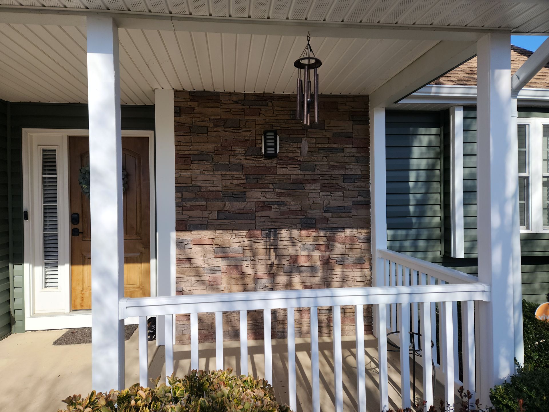 The front porch of a house with a wind chime on it