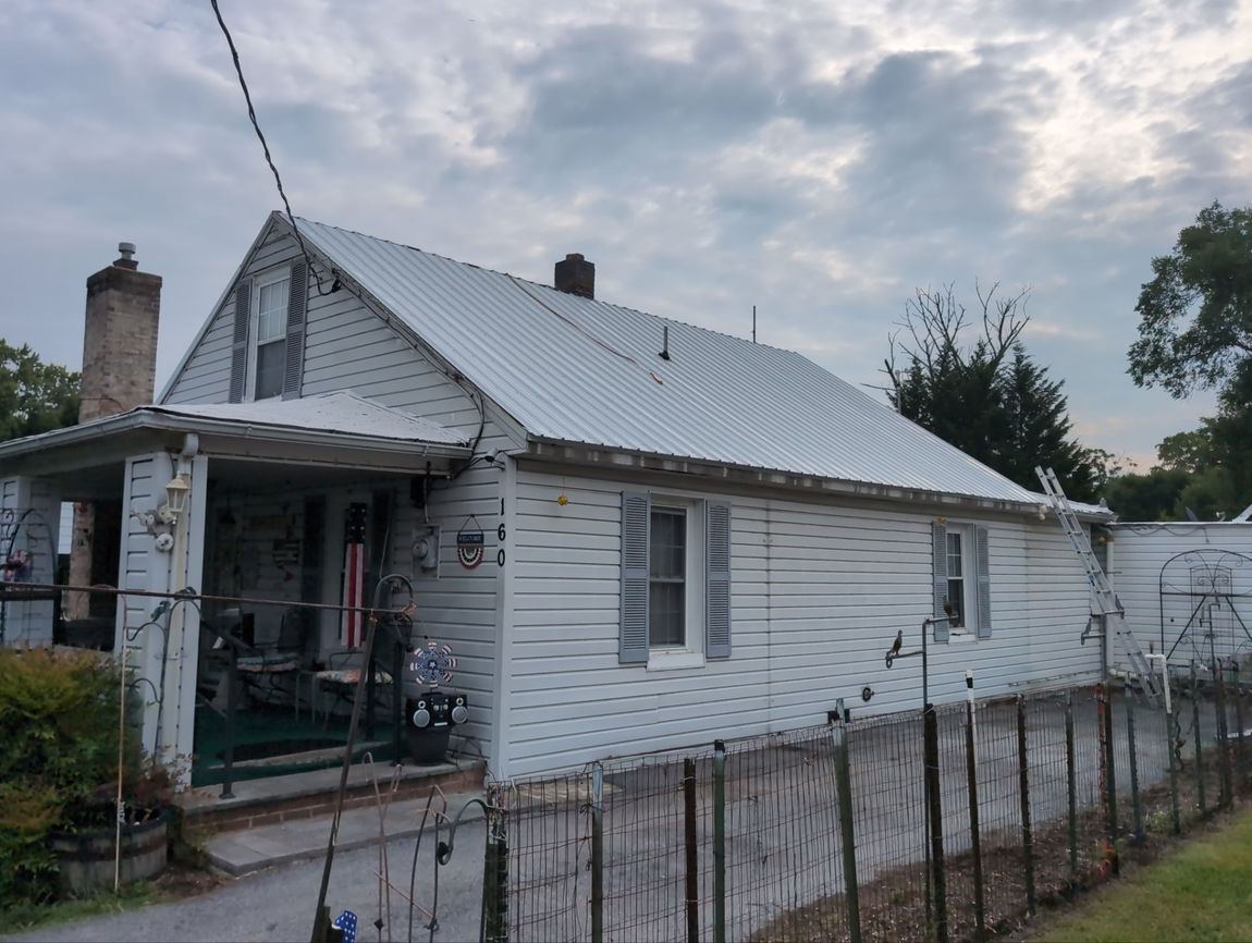 A white house with a metal roof and a fence around it