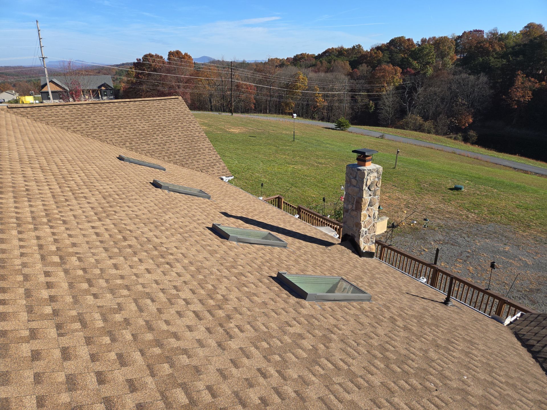 A roof with a chimney on top of it and a field in the background.