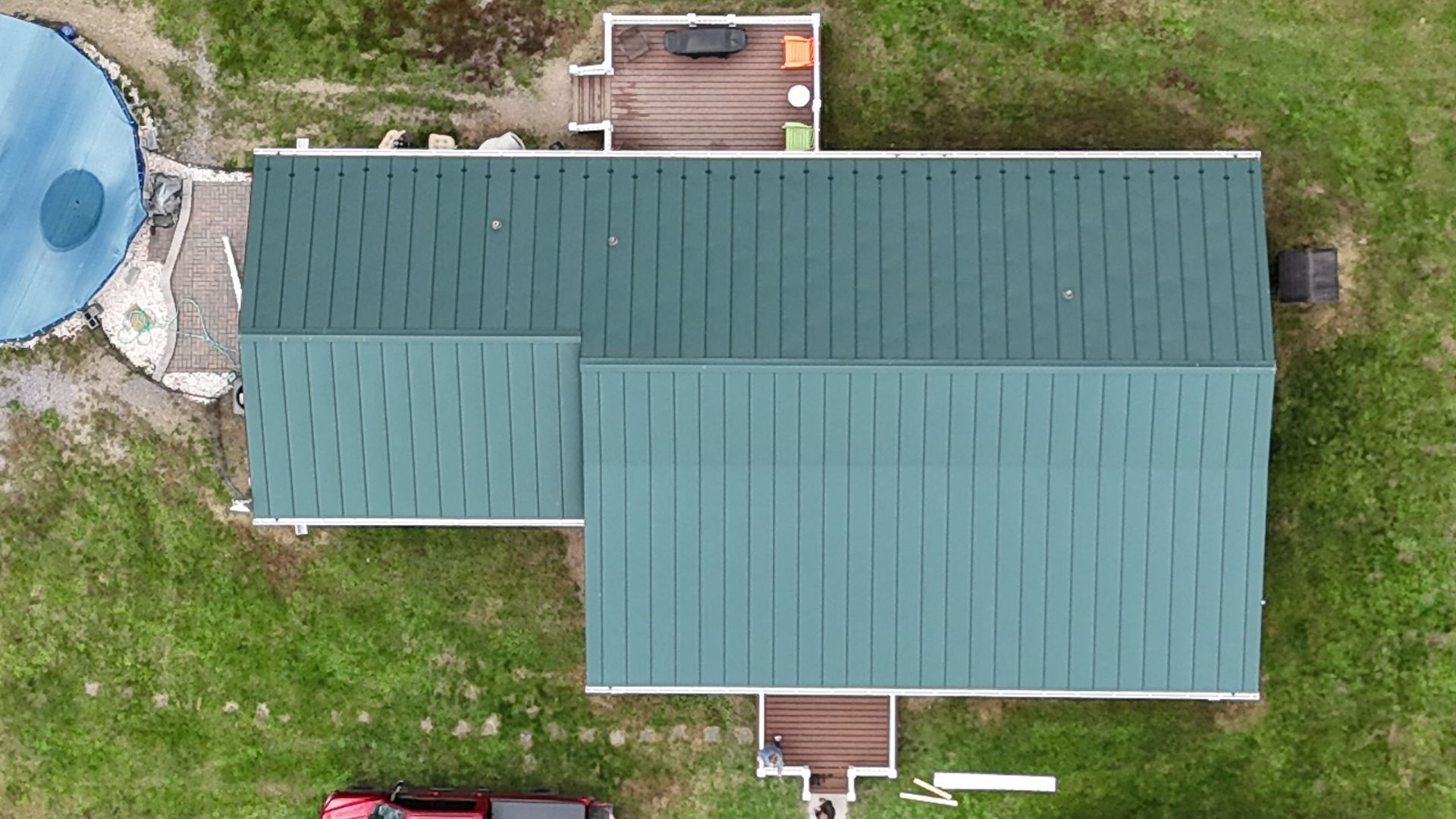 An aerial view of a house with a green roof and a red truck parked in front of it.