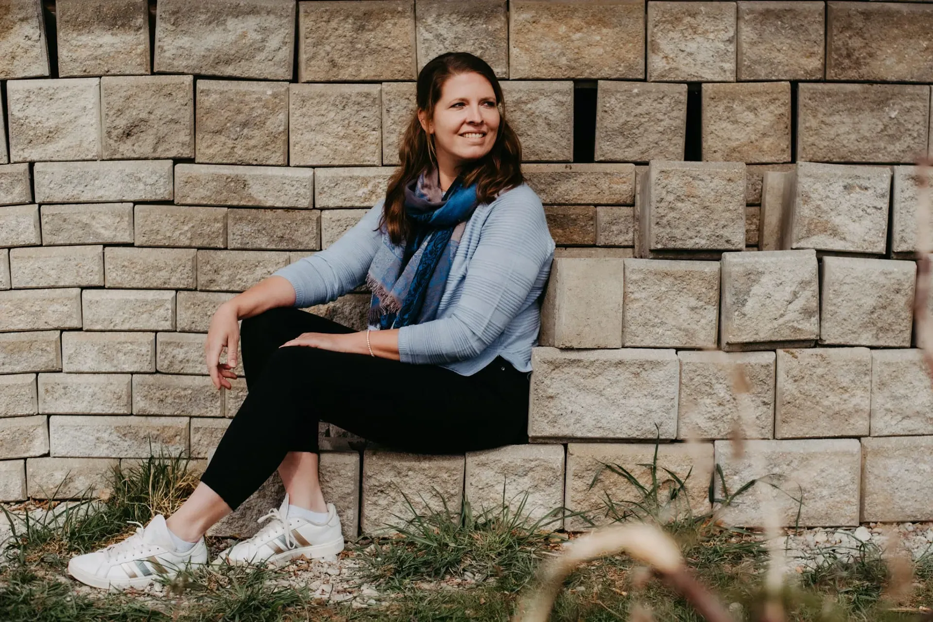 Julia sitzt auf einer Backsteinmauer.