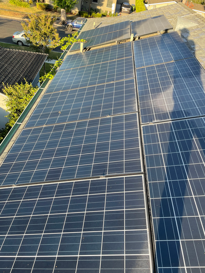 Solar panels installed on a dark roof; a shadow from the photographer is visible.
