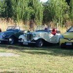 Three old cars are parked next to each other in a grassy field.