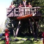 A group of young people are standing around a picnic table.