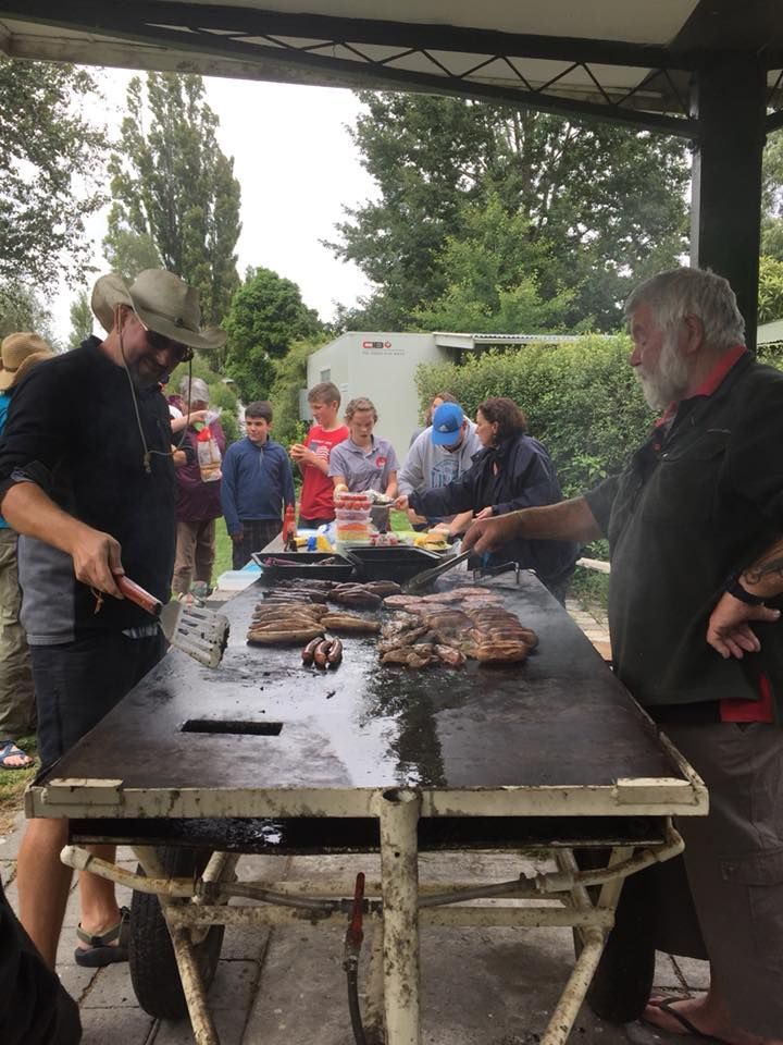 A group of people are standing around a table cooking food.