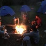 A bride and groom are kissing in the woods.