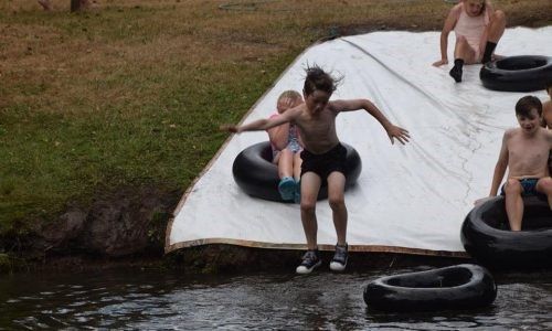 A group of children are playing on a tire slide in the water.