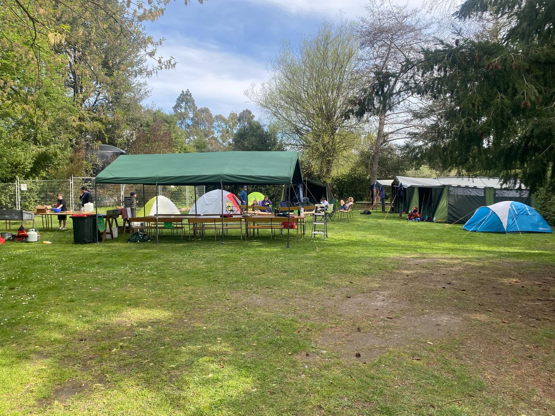 A tent is sitting in the middle of a grassy field next to a fire pit.