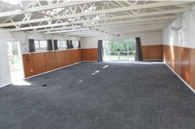 A large empty room with a carpeted floor and wooden walls.